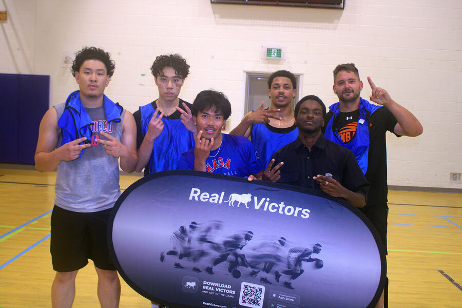 The blue team posing behind the Real Victors banner